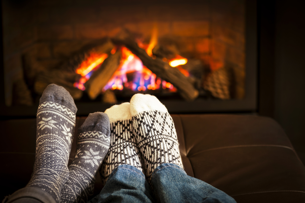 Picture of two pairs of feet in front of a cozy fireplace - cheap home insurance in Washington