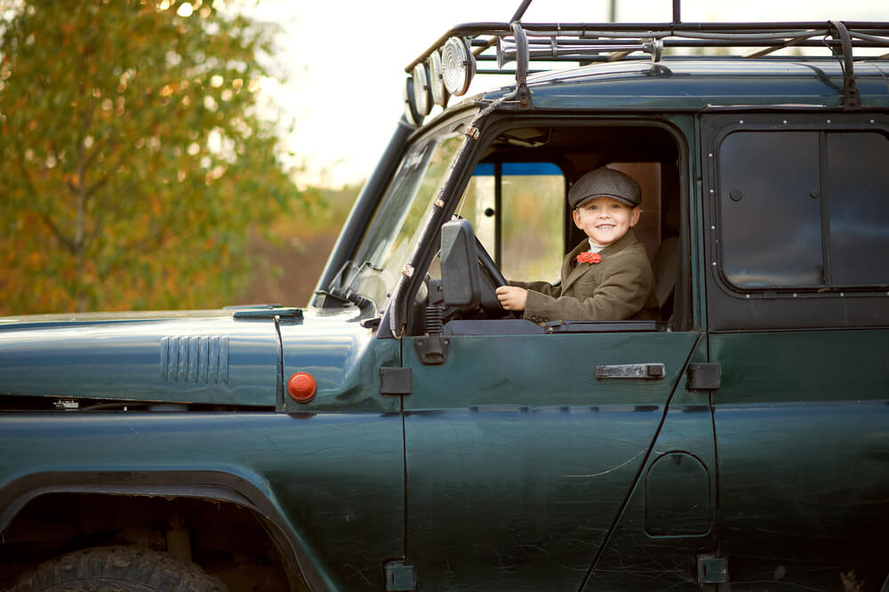 Smiling child behind the wheel of a Land Rover - cheap car insurance in Washington.